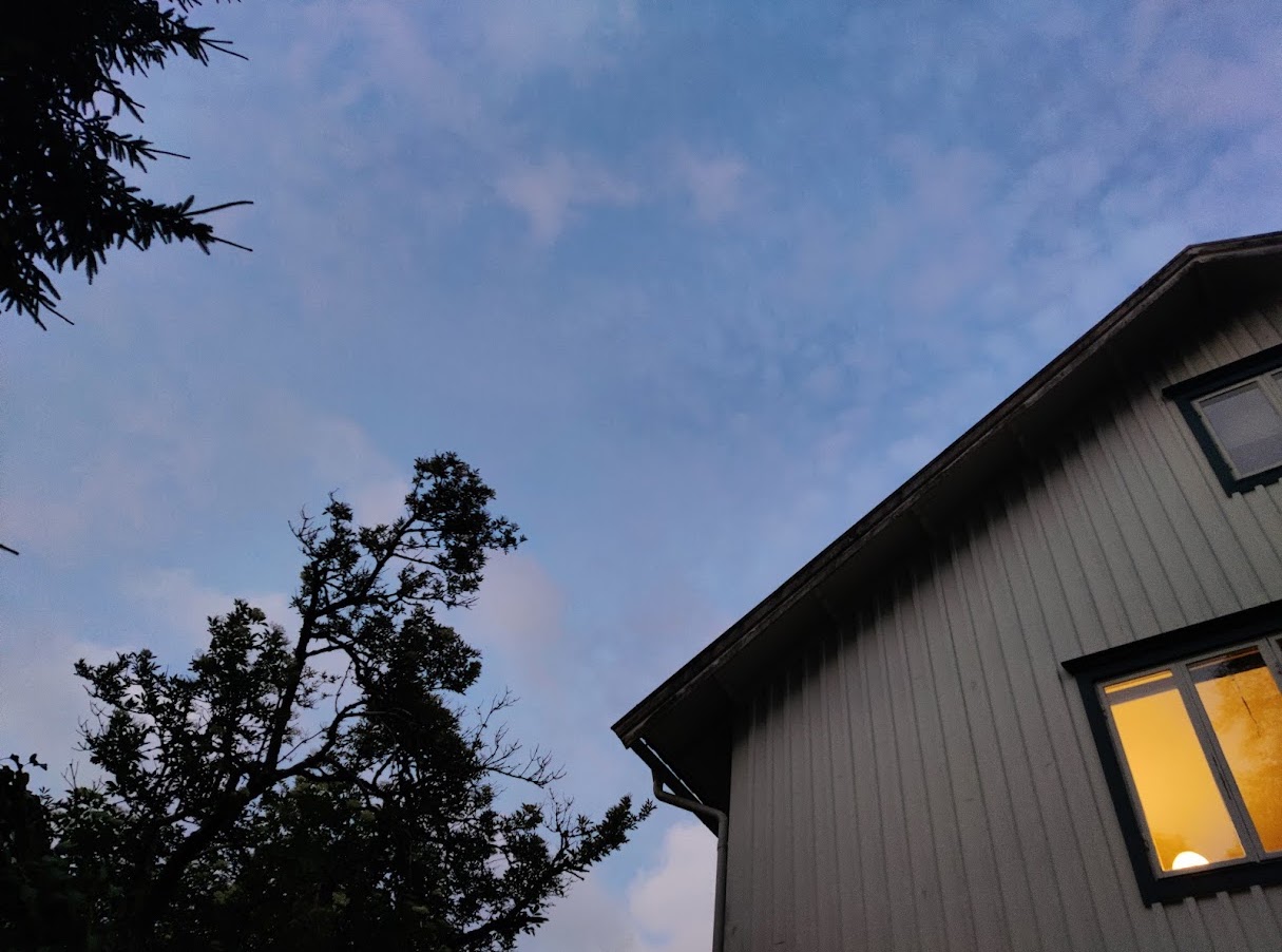 Midsummer twilight over a house with a yellow-lit window in Göteborg
